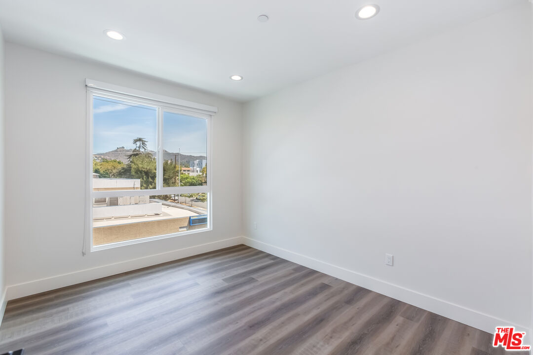 857 North Hayworth Avenue, Unit 403 Los Angeles, CA 90046 - Photo 39 of 52 an empty room with wooden floor and a window