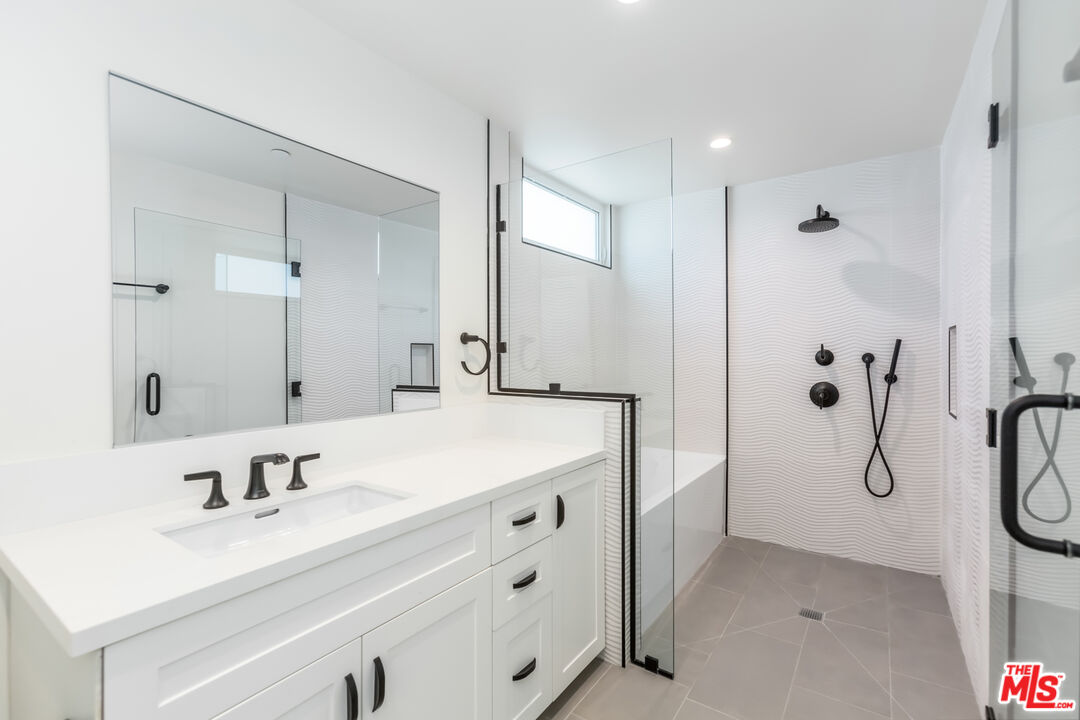 857 North Hayworth Avenue, Unit 403 Los Angeles, CA 90046 - Photo 9 of 52 a bathroom with a sink vanity granite tub shower and a mirror