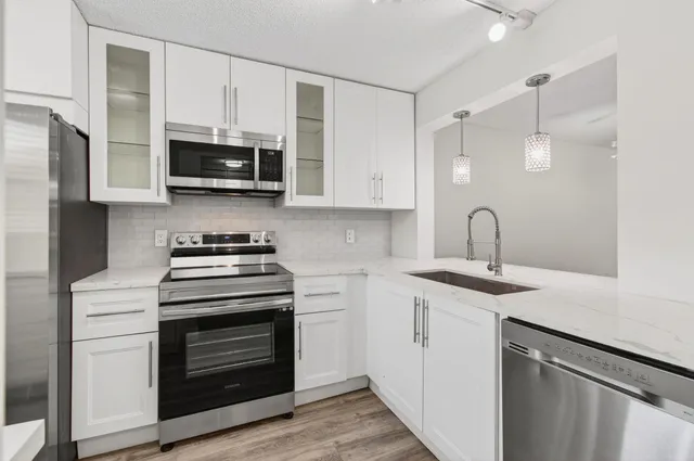 a kitchen with stainless steel appliances granite countertop a sink a stove and microwave