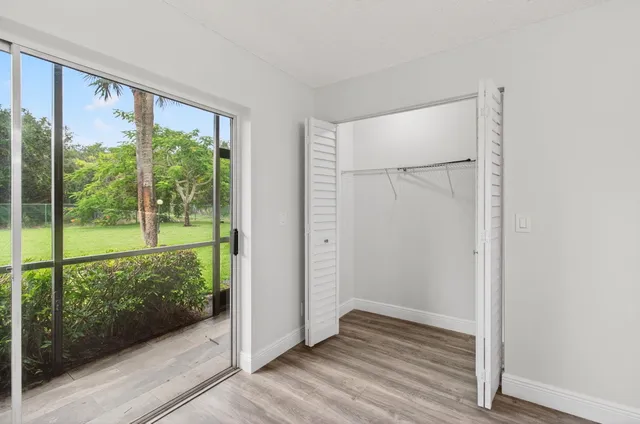 an empty room with wooden floor cabinet and windows