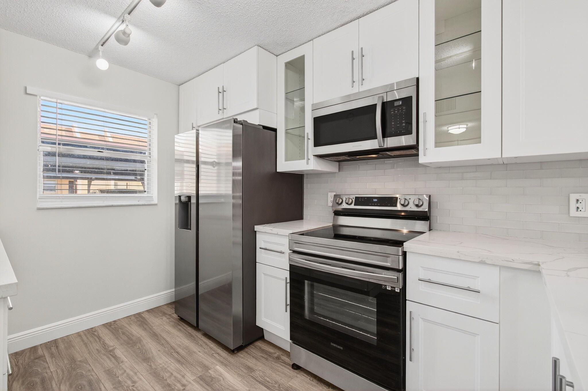 2975 Southwest 22nd Avenue, Unit 1070 Delray Beach, FL 33445 - Photo 22 of 60 a kitchen with stainless steel appliances white cabinets white stove a microwave and a refrigerator