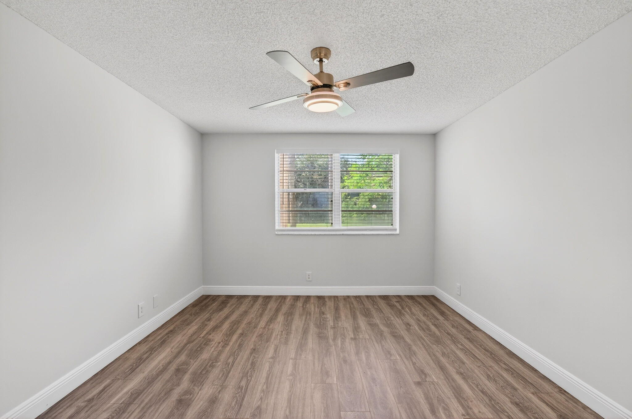2975 Southwest 22nd Avenue, Unit 1070 Delray Beach, FL 33445 - Photo 31 of 60 an empty room with wooden floor a ceiling fan and windows