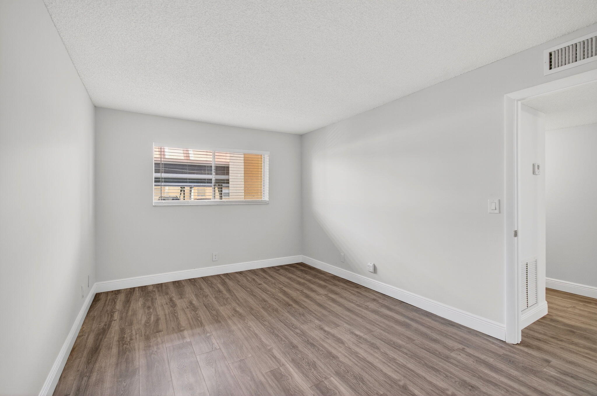 2975 Southwest 22nd Avenue, Unit 1070 Delray Beach, FL 33445 - Photo 38 of 60 an empty room with wooden floor and windows