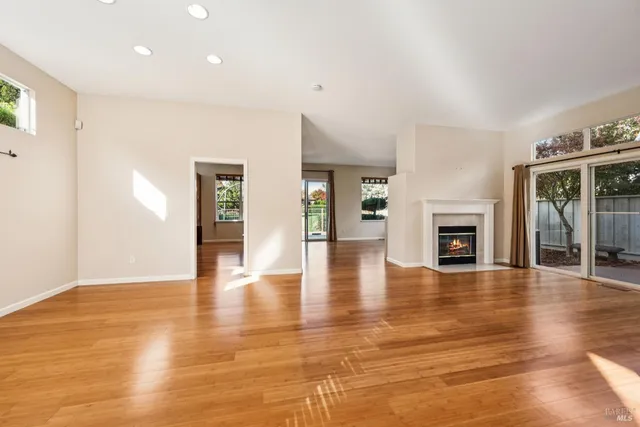 a view of an empty room with wooden floor and a fireplace