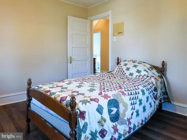 a view of empty room with wooden floor and way to kitchen