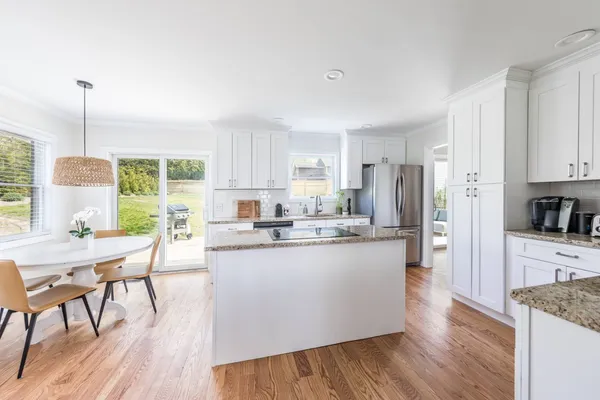 a kitchen with stainless steel appliances granite countertop a refrigerator a sink dishwasher a stove and white countertops with wooden floor