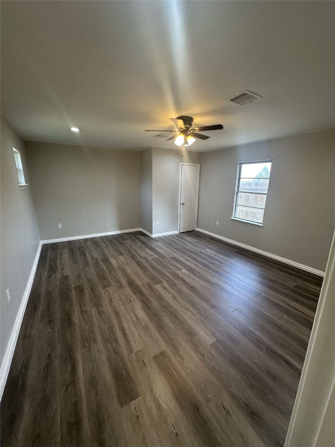 5847 Belcrest Street Houston, TX 77033 - Photo 2 of 7 an empty room with wooden floor chandelier fan and windows