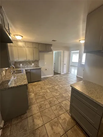 a kitchen with kitchen island a sink granite counter tops and a stove