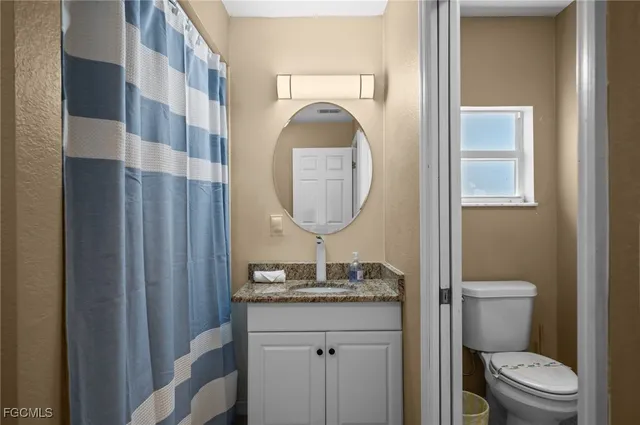 a bathroom with a granite countertop toilet and a sink