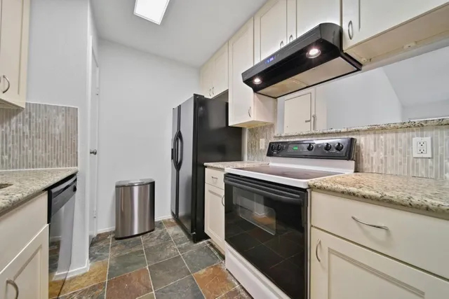 a kitchen with stainless steel appliances granite countertop a sink a stove a refrigerator and cabinets