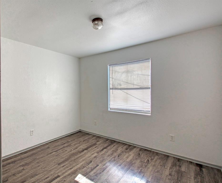 916 Isbell Road, Unit D Fort Worth, TX 76114 - Photo 7 of 13 an empty room with wooden floor and windows
