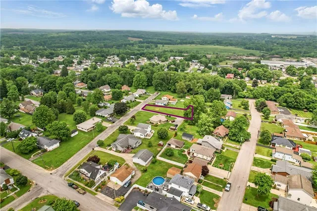 an aerial view of a residential houses with outdoor space and trees