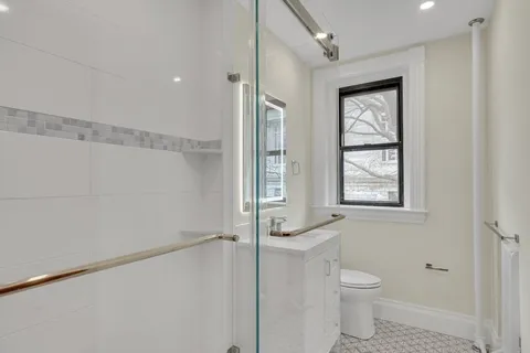 a bathroom with a granite countertop sink a toilet and shower