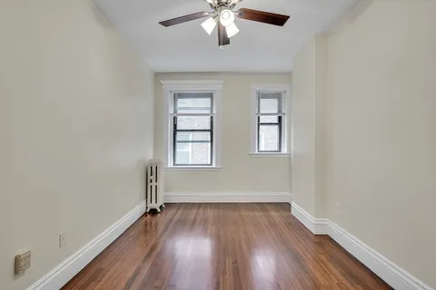 an empty room with wooden floor chandelier and windows