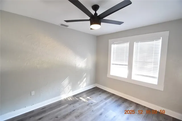 a view of an empty room with a window and wooden floor
