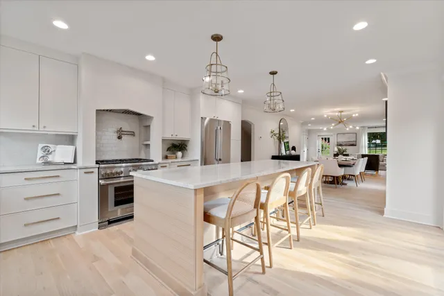 a kitchen with stainless steel appliances kitchen island granite countertop a stove a sink a dining table and chairs with wooden floor