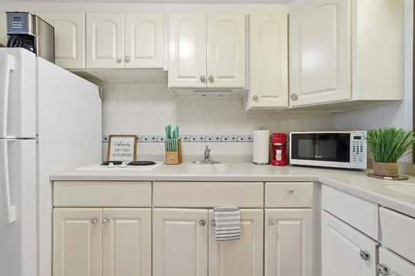 a kitchen with white cabinets and white appliances