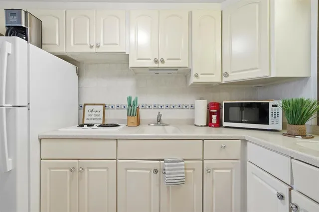 a kitchen with white cabinets and white appliances