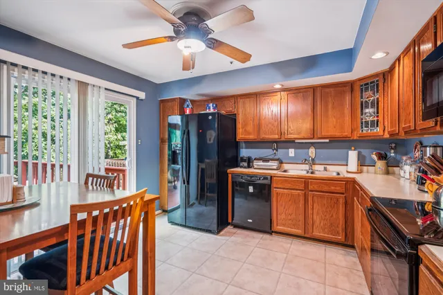 a kitchen with stainless steel appliances granite countertop a refrigerator a sink dishwasher a stove and a dining table with wooden floor