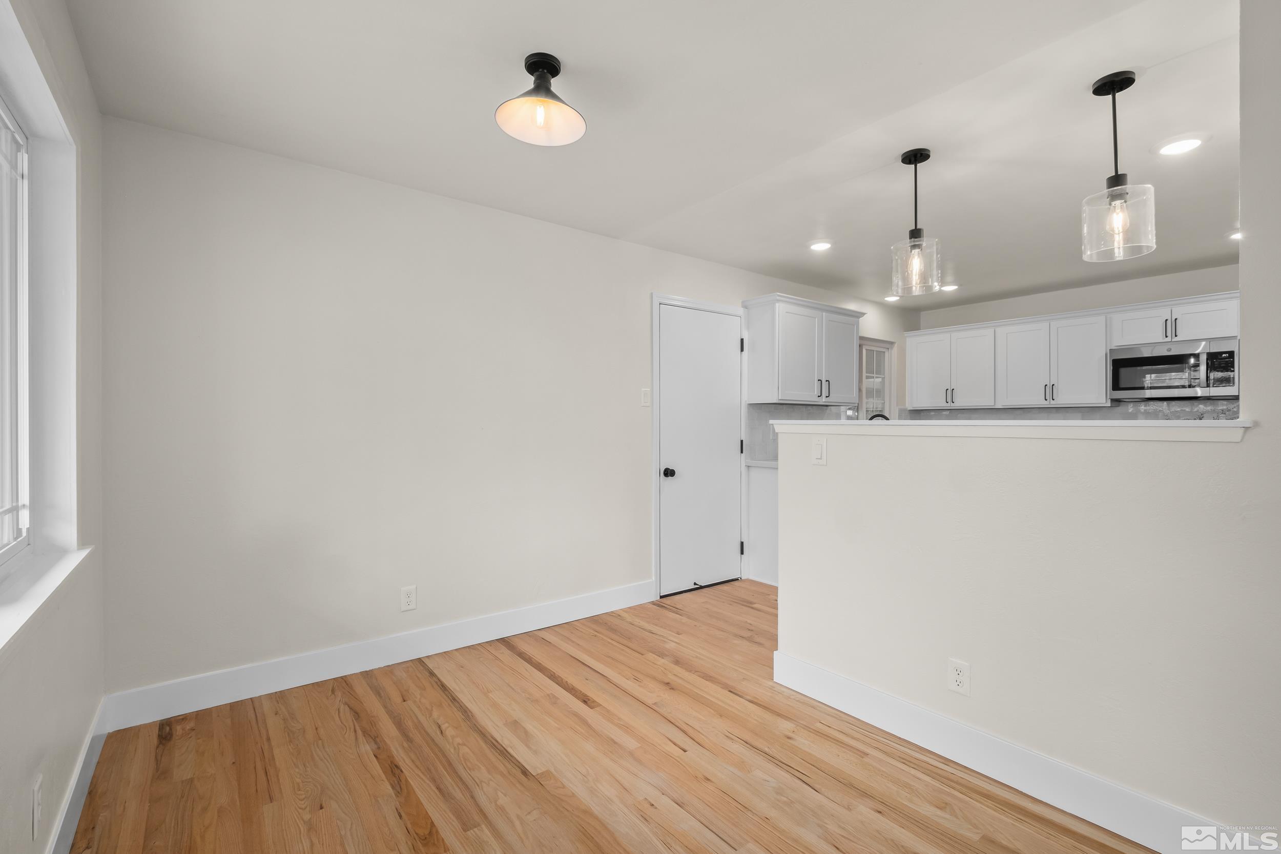 1220 Vassar Street Reno, NV 89502 - Photo 7 of 36 wooden floor in an empty room with a kitchen