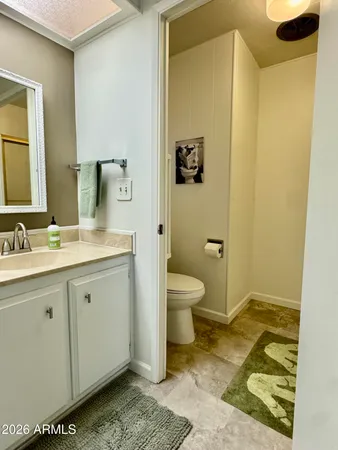 a spacious bathroom with a granite countertop toilet sink and mirror