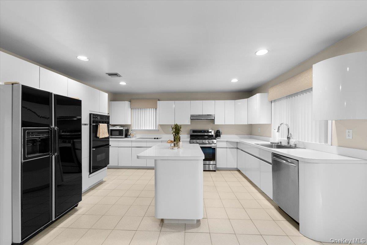 47 Berkshire Road Great Neck, NY 11023 - Photo 20 of 40 Kitchen featuring black appliances, light countertops, recessed lighting, white cabinetry, and a center island