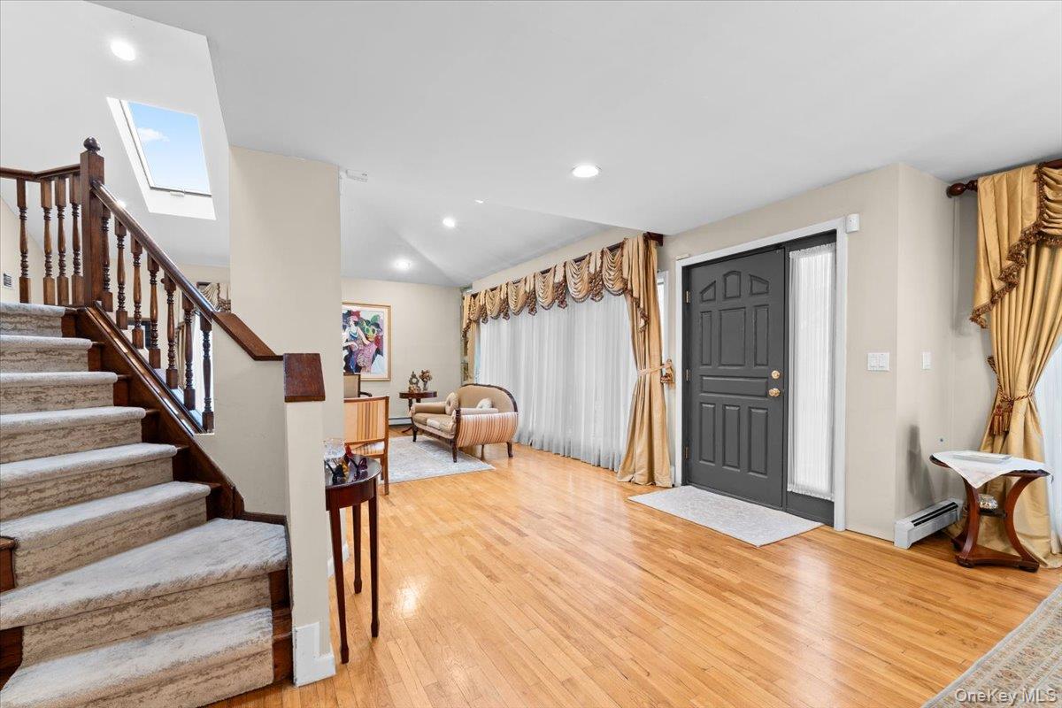 47 Berkshire Road Great Neck, NY 11023 - Photo 3 of 40 Entrance foyer featuring light wood-type flooring, stairway, lofted ceiling, recessed lighting, and a baseboard radiator