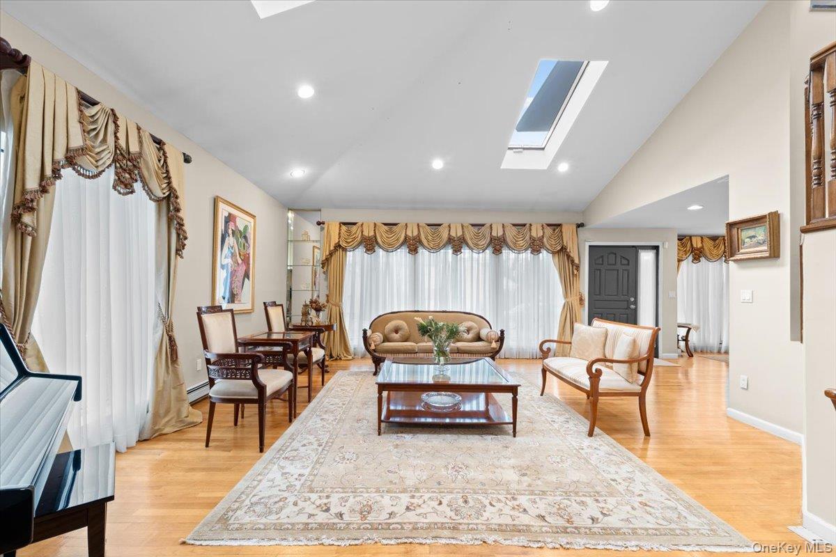47 Berkshire Road Great Neck, NY 11023 - Photo 7 of 40 Living room featuring a skylight, light wood-type flooring, recessed lighting, and high vaulted ceiling