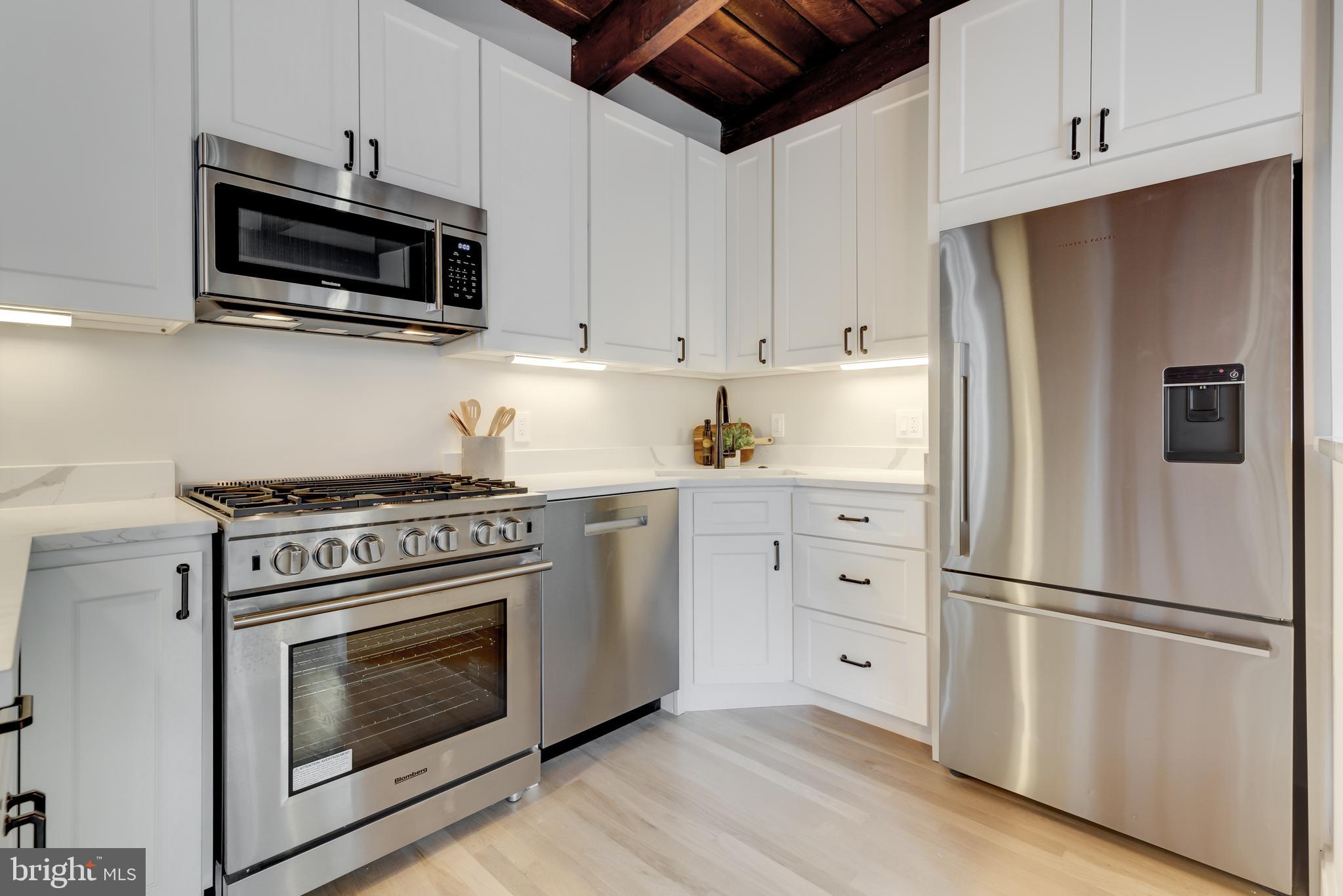 1314 Vermont Avenue Northwest, Unit CH6 Washington, DC 20005 - Photo 13 of 23 a kitchen with stainless steel appliances white cabinets white stove a microwave and a refrigerator