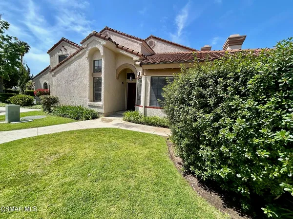 a view of a house with brick walls and a yard with plants