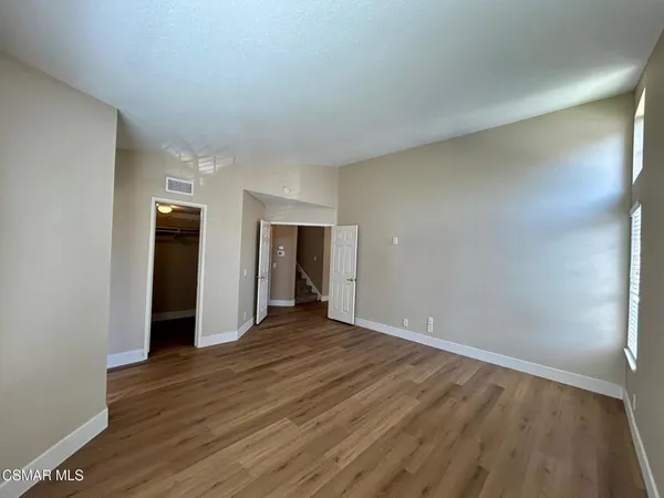 a view of an empty room with wooden floor and closet