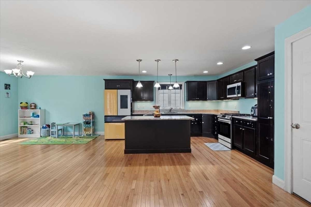 28 McIntosh Drive, Unit 22 Stow, MA 01775 - Photo 11 of 38 a kitchen with stainless steel appliances kitchen island granite countertop a refrigerator a stove top oven and a wooden floors
