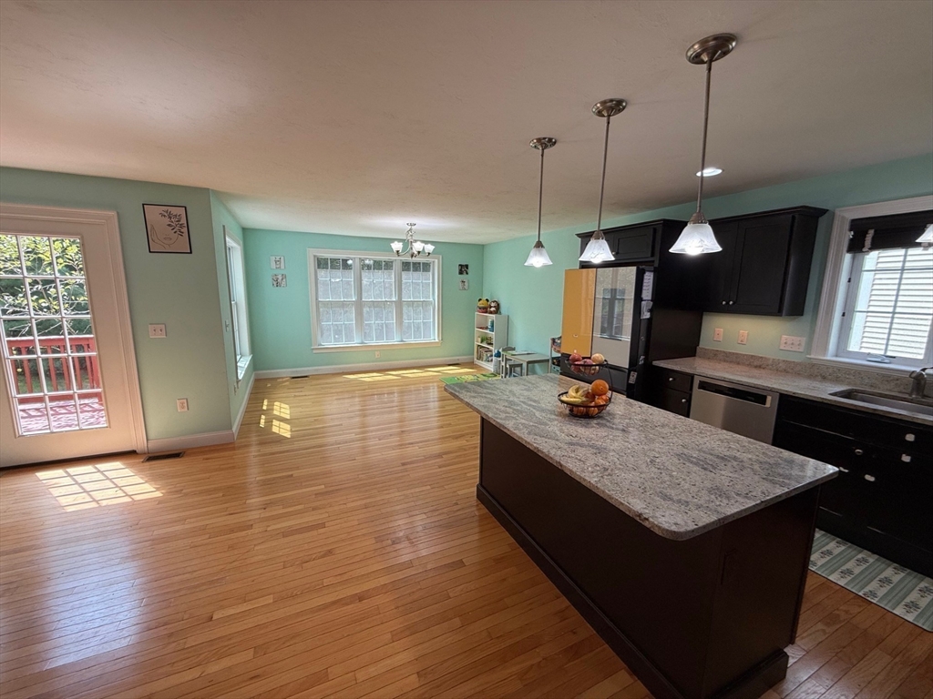 28 McIntosh Drive, Unit 22 Stow, MA 01775 - Photo 13 of 38 a kitchen with kitchen island granite countertop wooden cabinets a sink and a wooden floor