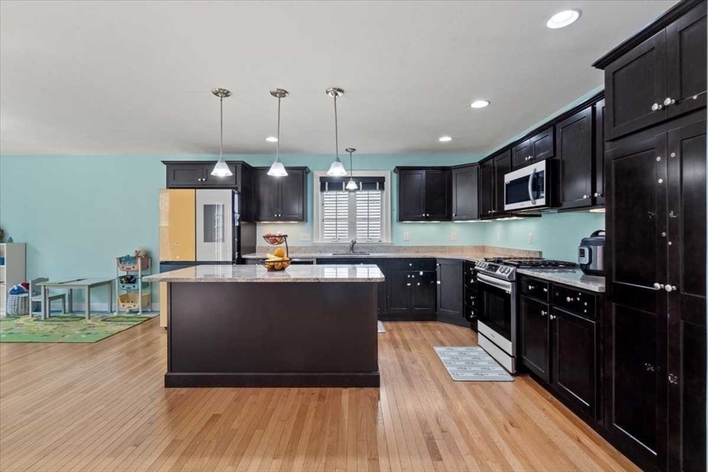 28 McIntosh Drive, Unit 22 Stow, MA 01775 - Photo 14 of 38 a kitchen with kitchen island granite countertop wooden floors stainless steel appliances and a sink