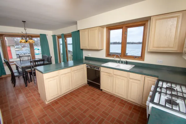 a large white kitchen with granite countertop a stove a sink a dining table and chairs