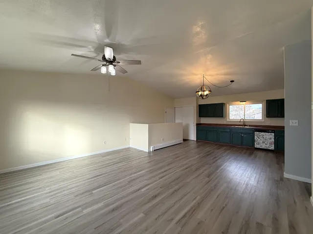 a view of an empty room with wooden floor and a ceiling fan