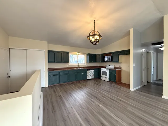a kitchen with stainless steel appliances granite countertop a sink cabinets and wooden floor