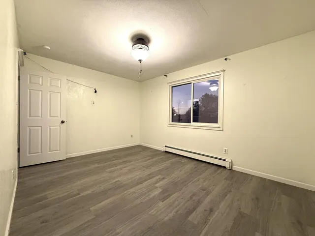 an empty room with wooden floor chandelier and windows