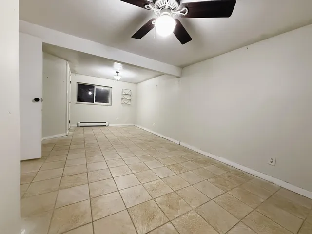 a view of an empty room with a ceiling fan and window