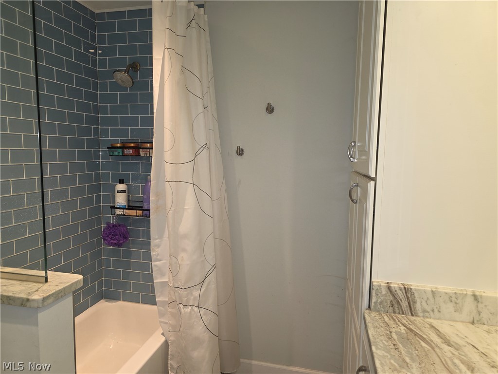 2868 Shade Road Akron, OH 44333 - Photo 34 of 49 Bathroom featuring a tub and shower combination with blue subway tile surround, polished chrome shower head, and a built-in shelving system