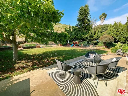 a view of a patio with table and chairs potted plants and large tree