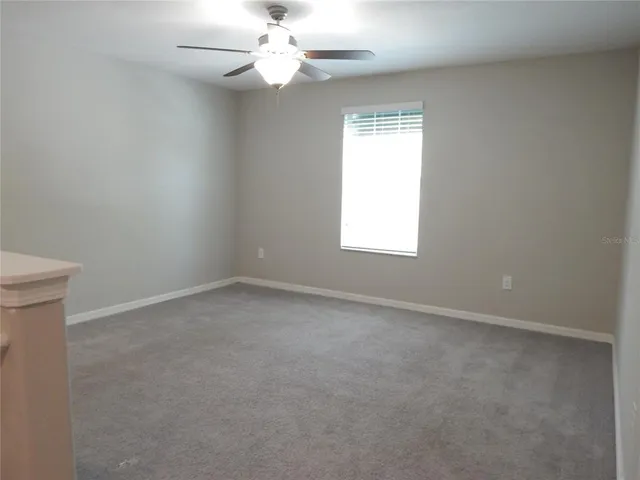 an empty room with a window and a fan