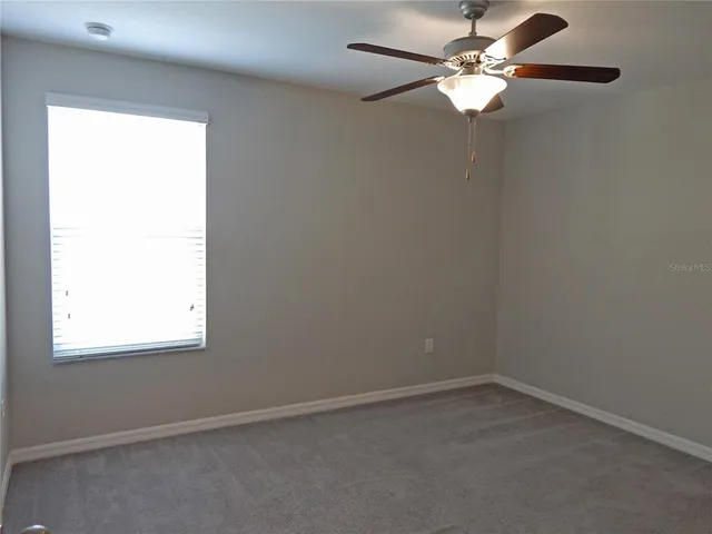 an empty room with a window and a fan