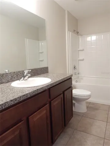 a bathroom with a granite countertop sink toilet a mirror and a bathtub