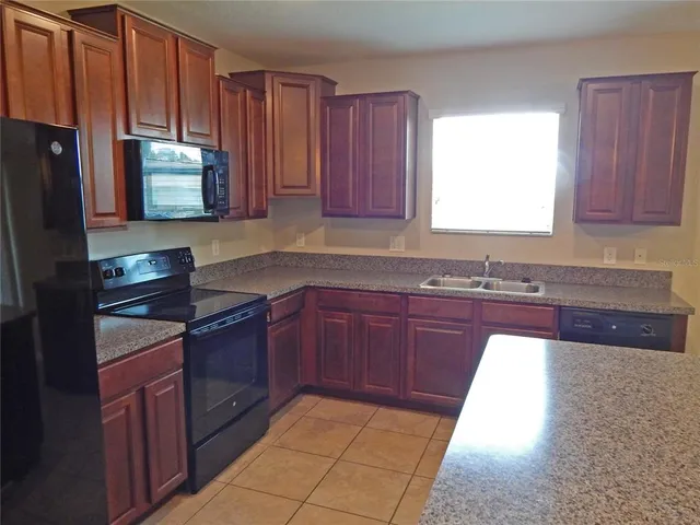a kitchen with granite countertop wooden cabinets stainless steel appliances a sink and a window