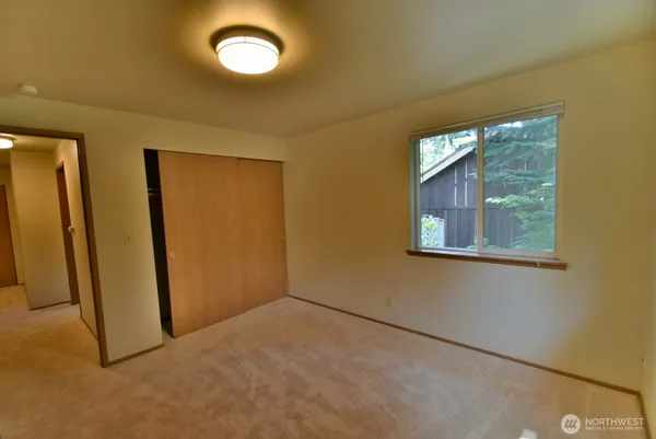 an empty room with a window and closet area