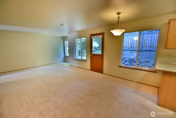 an empty room with chandelier fan and windows