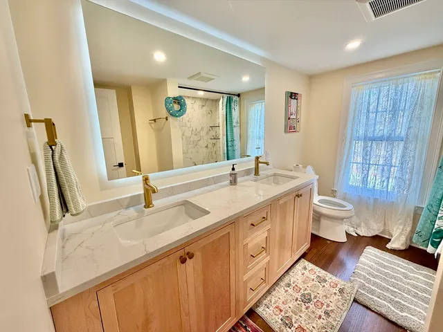 a spacious bathroom with a double vanity sink toilet and a mirror