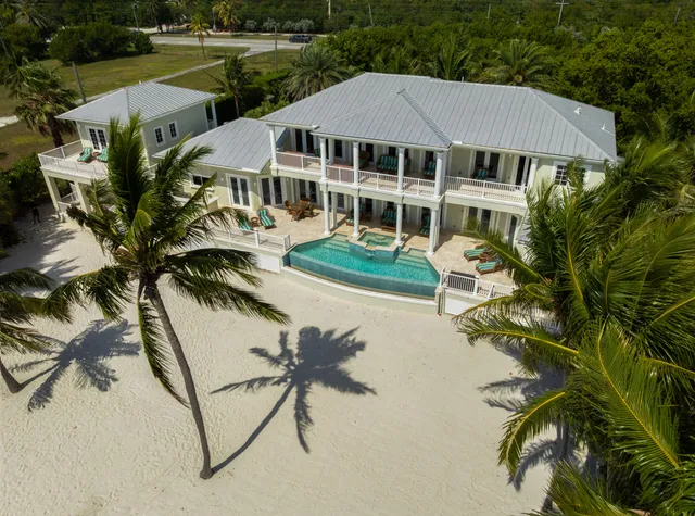 a view of a white house with a yard table and chairs