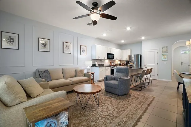 a living room with furniture kitchen view and a chandelier